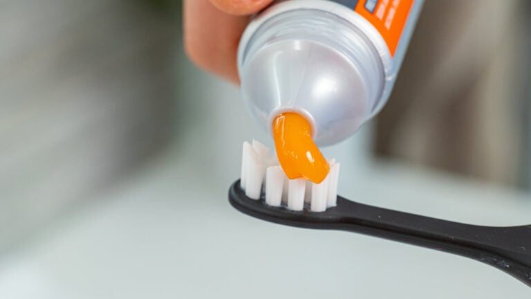 Toothpaste being put on toothbrush head