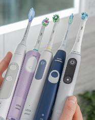 Sonicare and Oral-B toothbrushes being held in hand