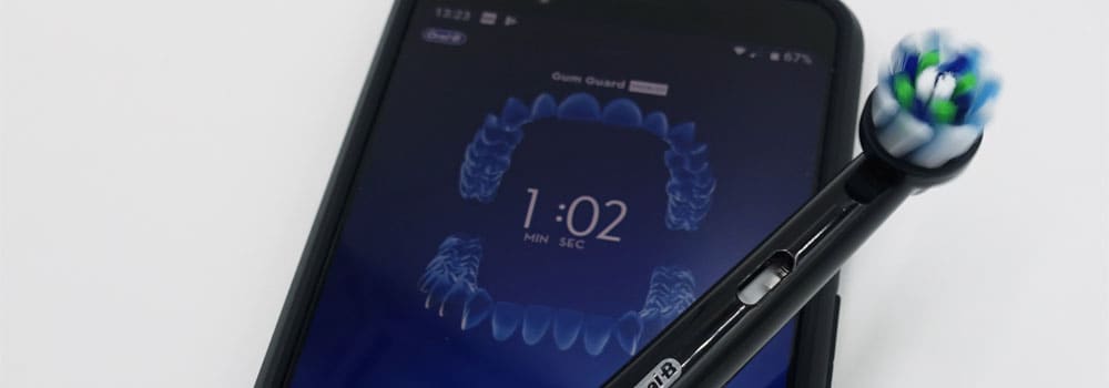 Close up of Oral-B brush head placed over smartphone with the Oral-B app on screen
