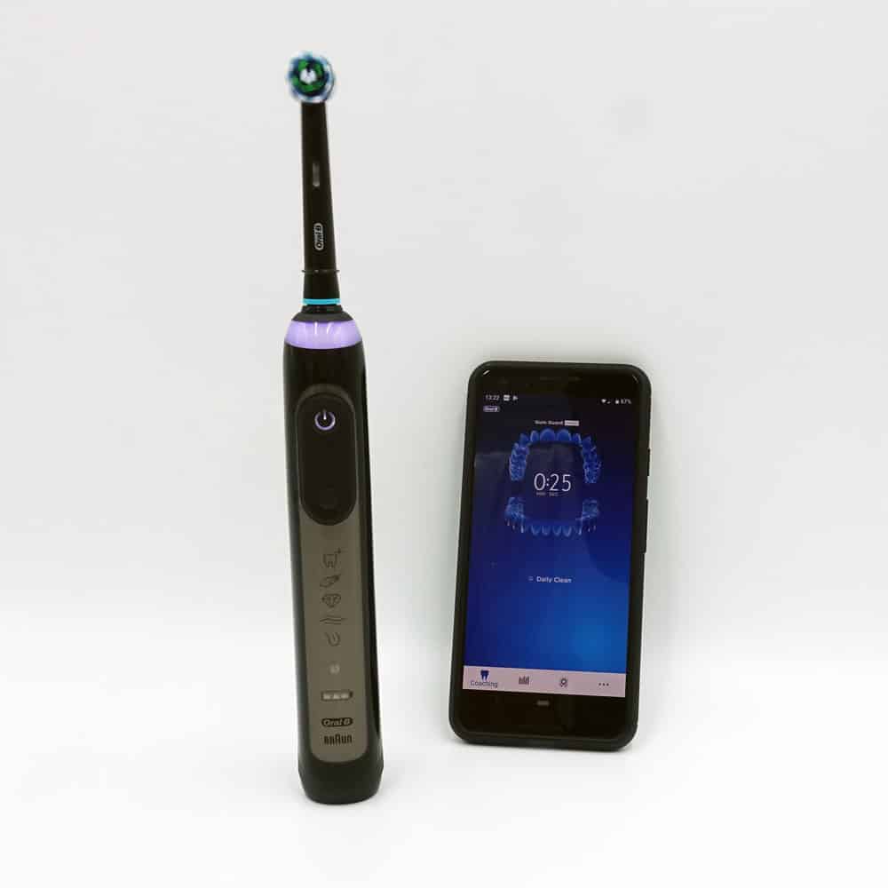 Oral-B Genius X next to smartphone with app on screen