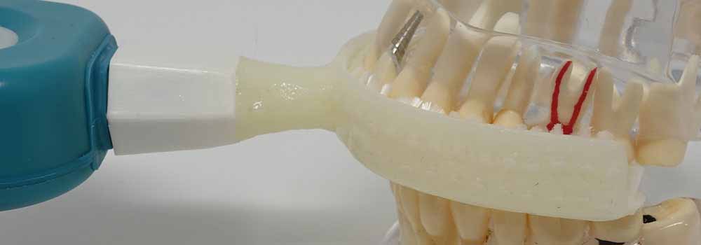 Y-brush mouthpiece toothbrush being used on a model of teeth