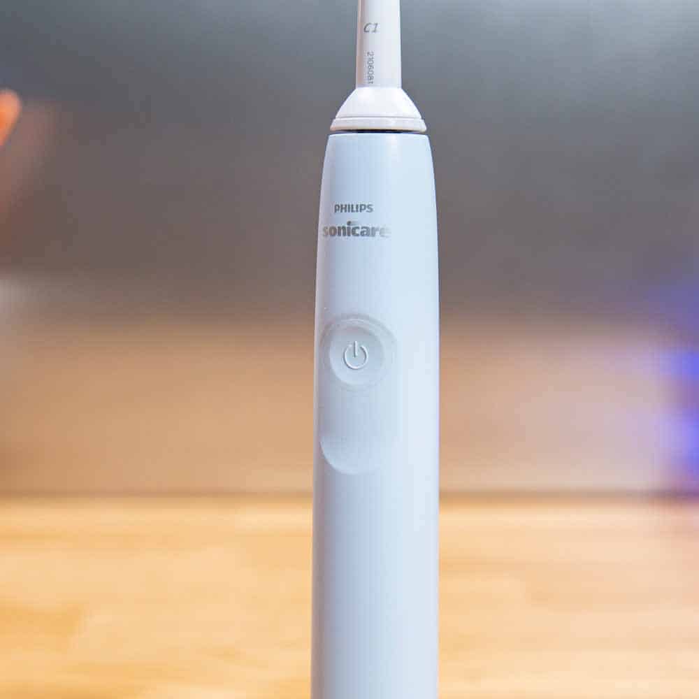 Close up on the single power button of the Philips 2100 Series electric toothbrush