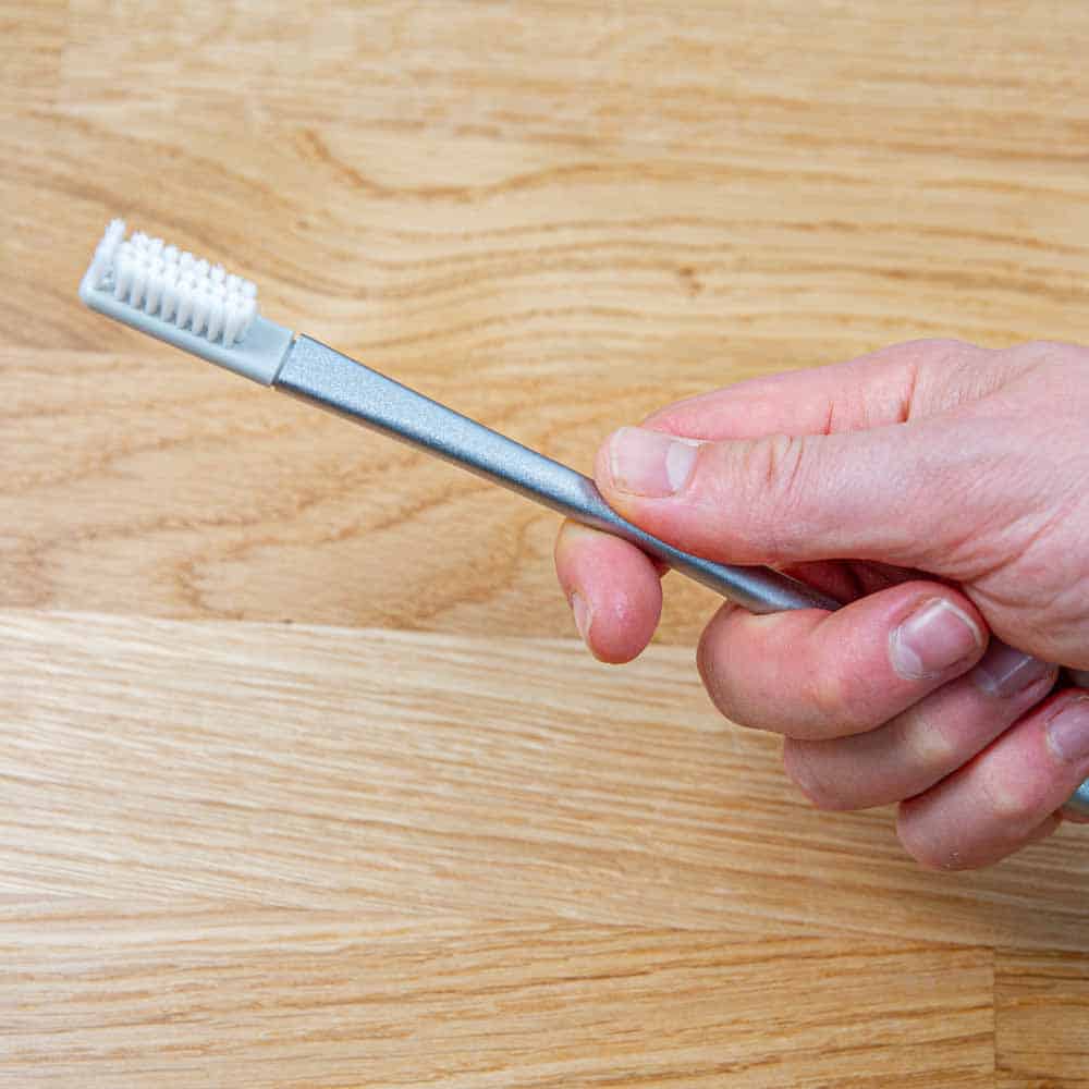 Tooth metal toothbrush in hand