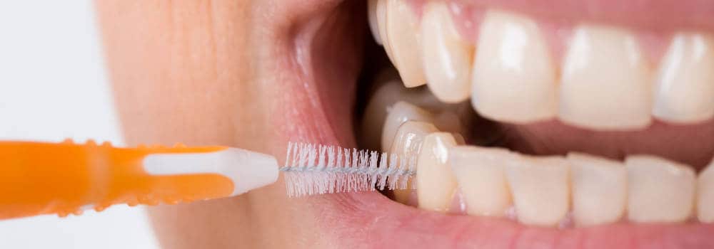 person using interdental brush on front teeth