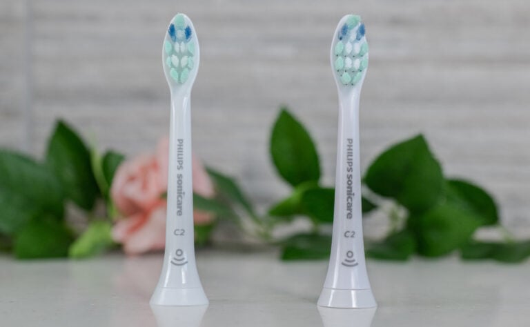 Two electric toothbrush heads stood next to each other.