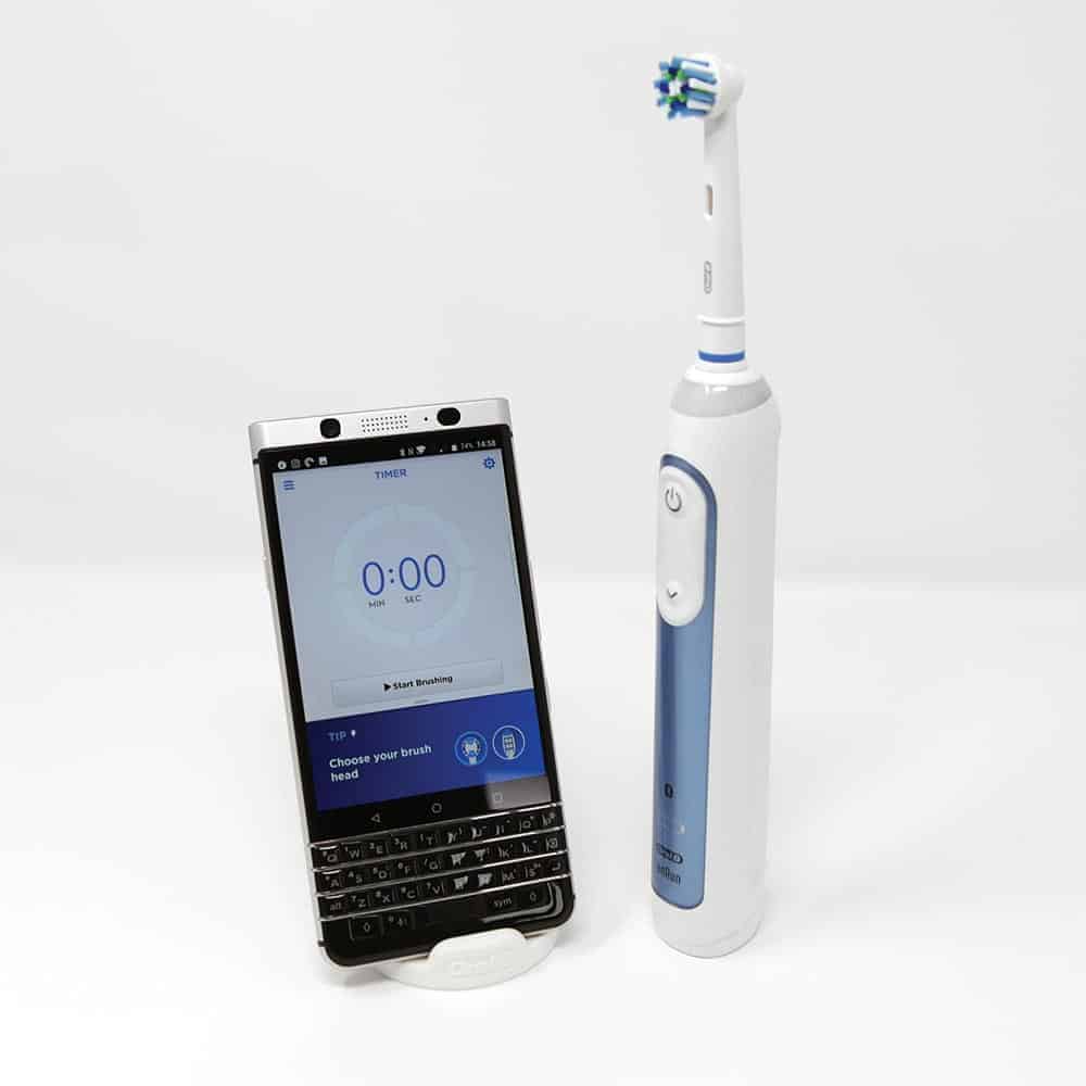 Oral-B electric toothbrush stood next to smartphone with app