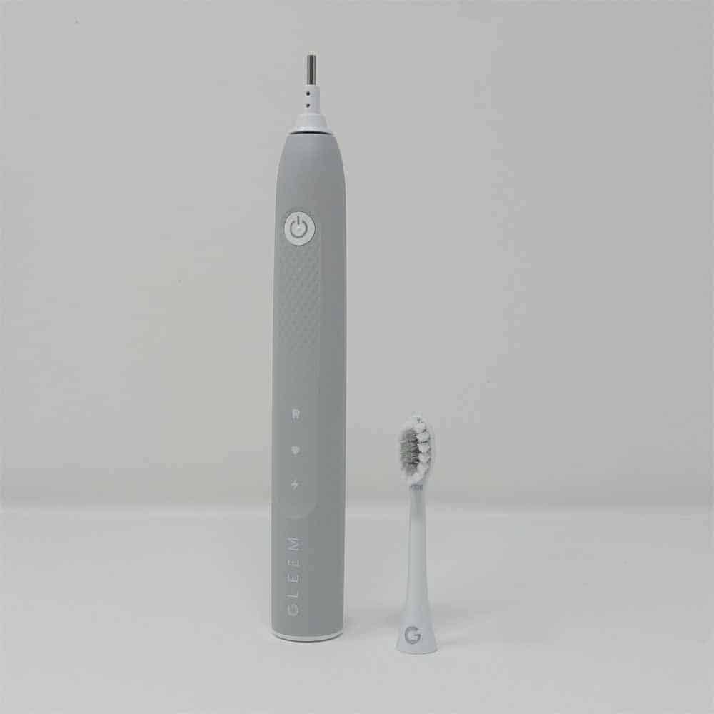 Grey Gleem toothbrush with head off stood next to it