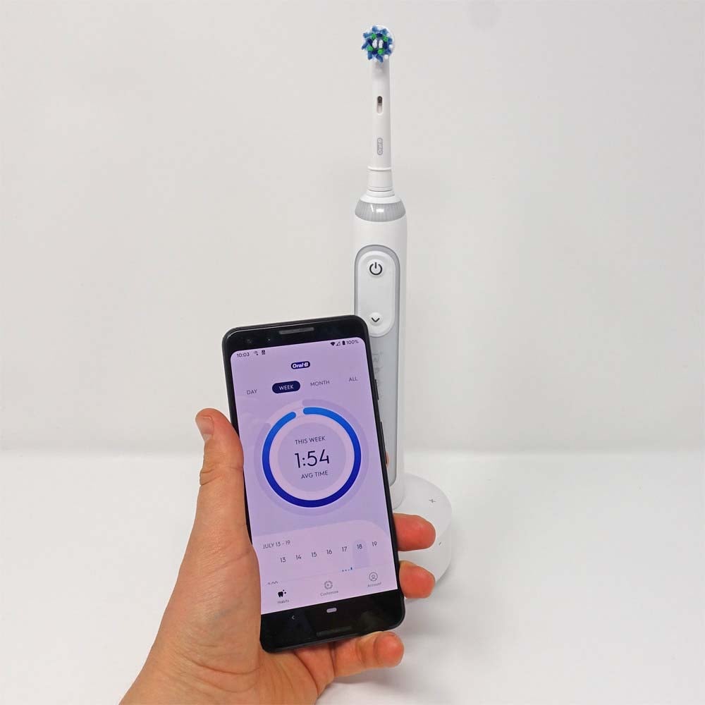 Oral-B Guide toothbrush & Connect app on phone in hand