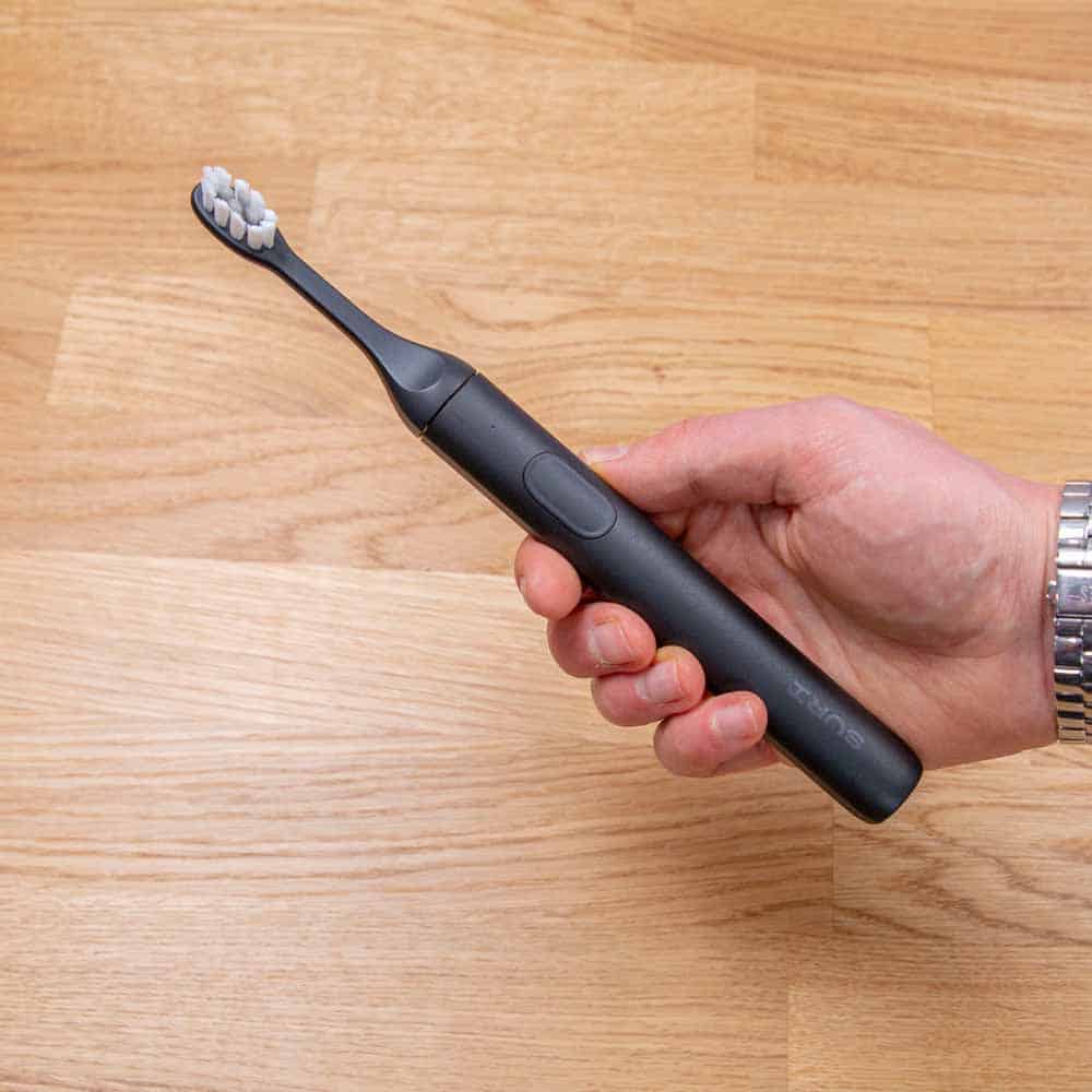 Black SURI sonic toothbrush in hand