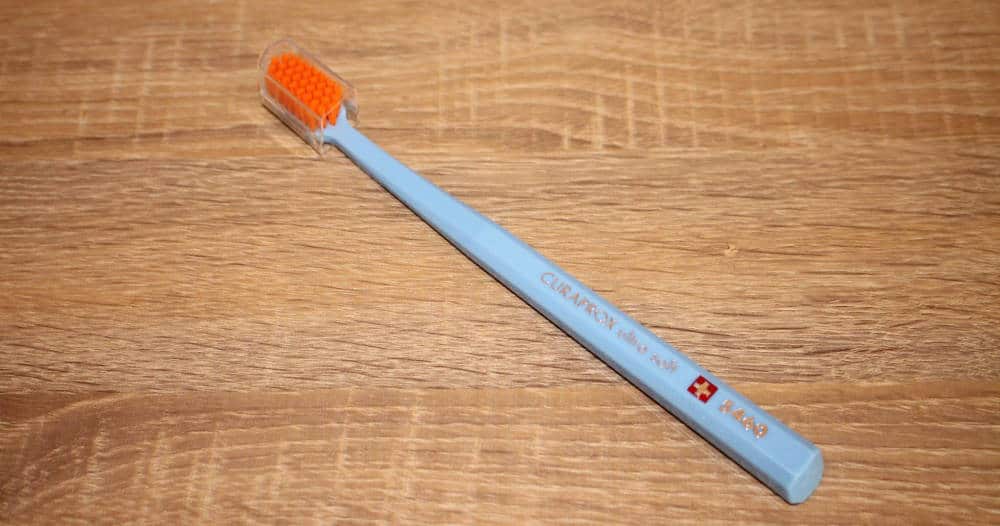 Curaprox CS450 light blue with orange bristles with brush head cover on