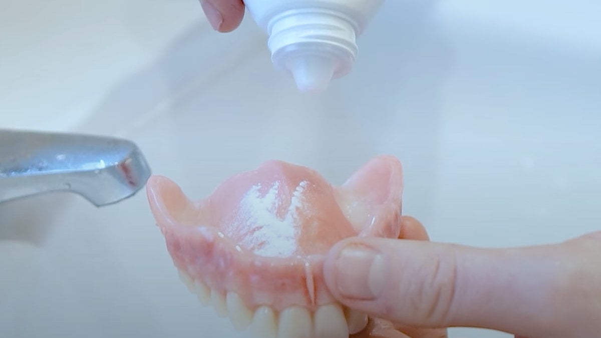 Denture powder being applied to denture