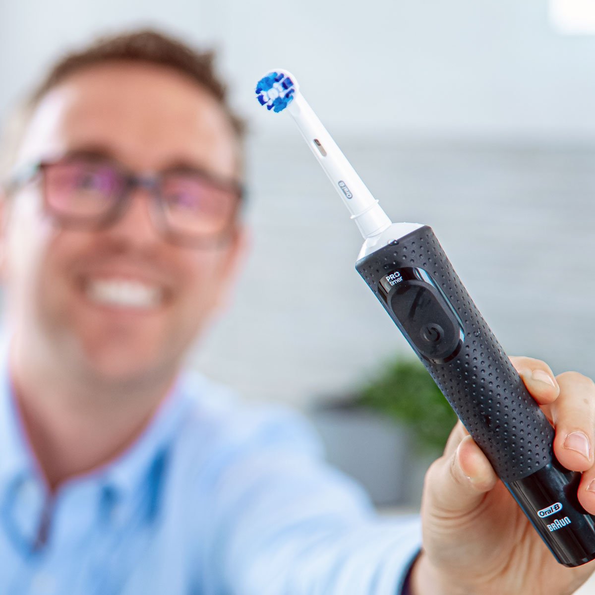 Oral-B Pro 500 close to the camera with man in background holding it