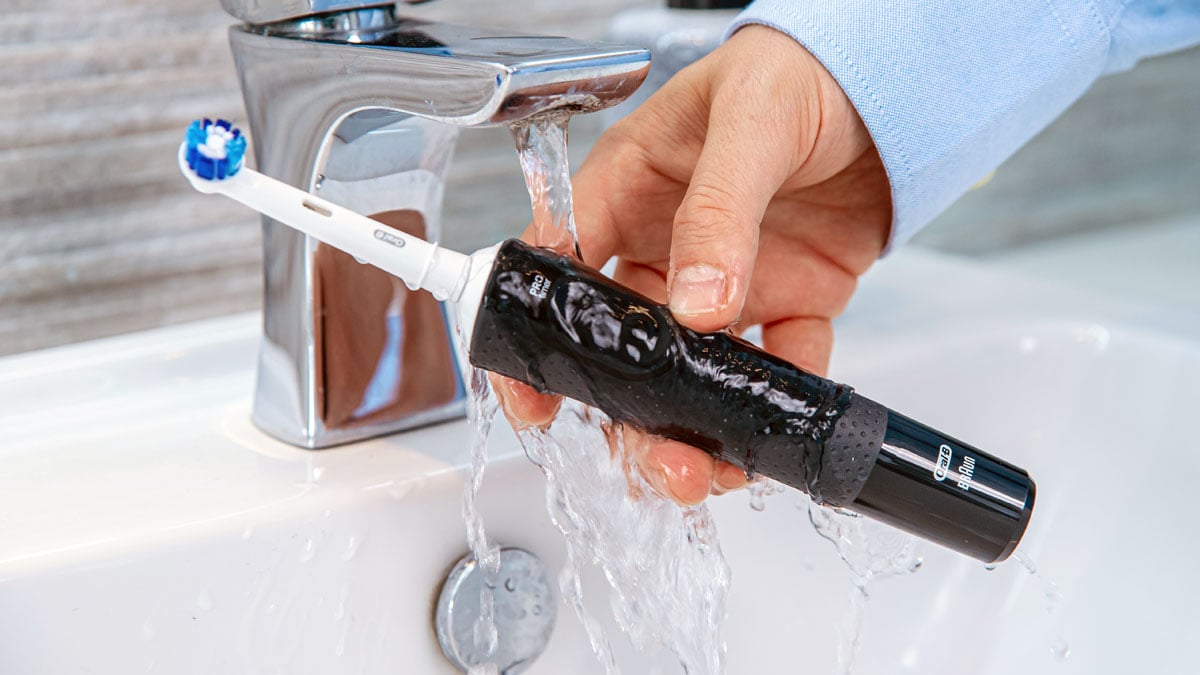 Oral-B Pro 500 being rinsed under a tap