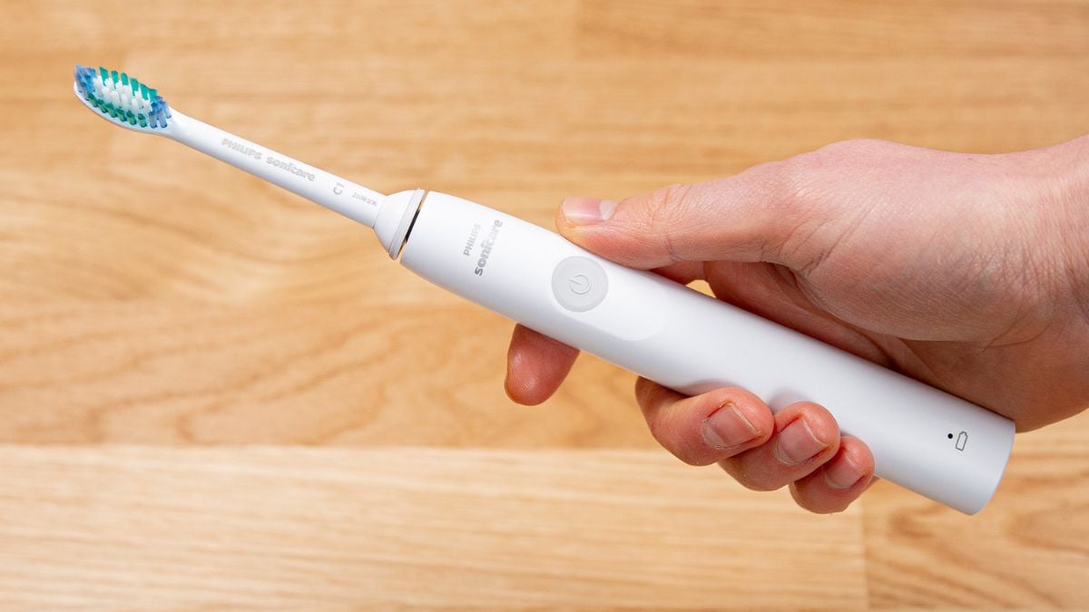 A Sonicare 1100 Series toothbrush held in a mans hand